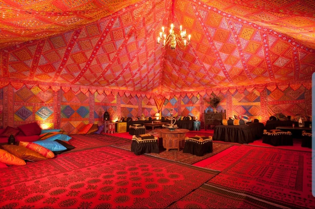 Stretch tent interior dressed with patterned draping, chandelier and lounge seating