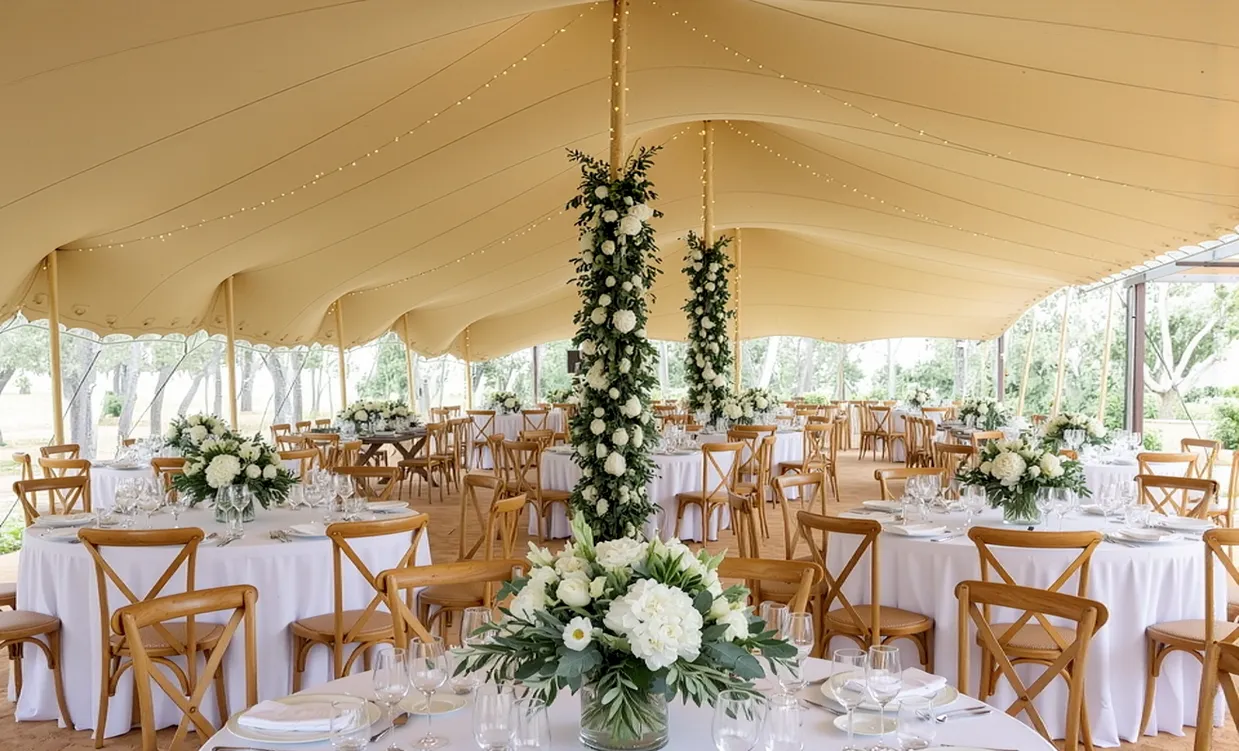 Elegant wedding table setting under a stretch tent with floral centrepieces
